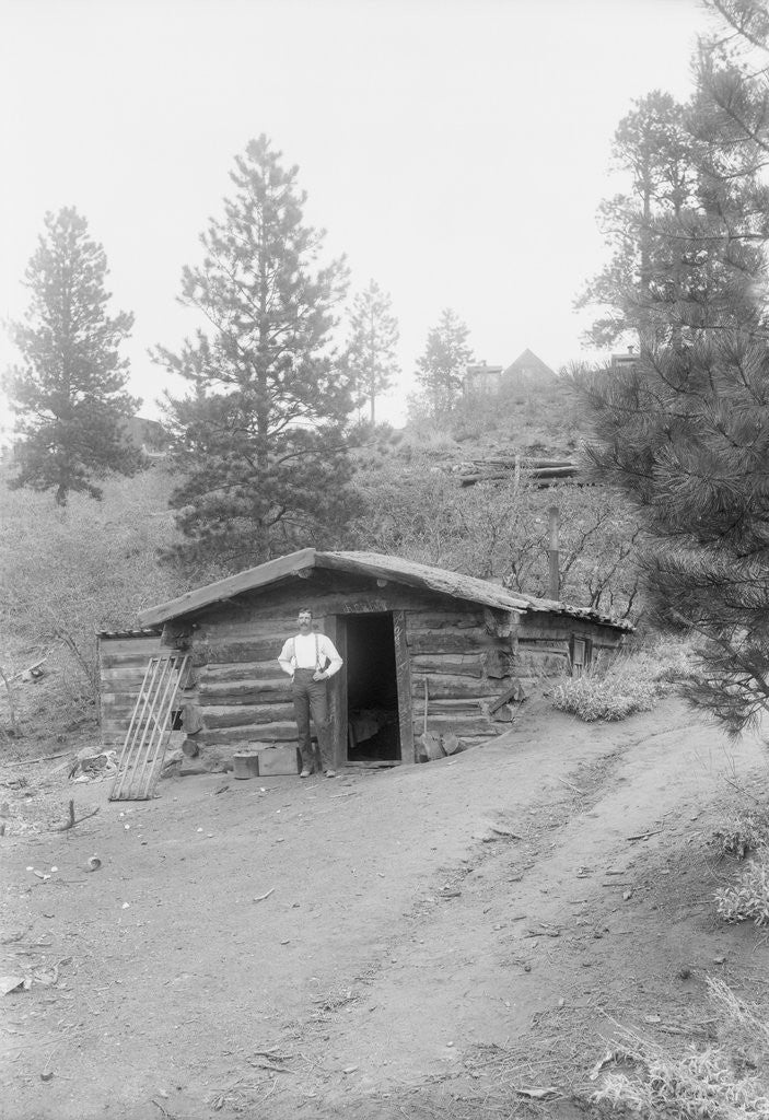 Detail of Man Standing in Front of Log Cabin by Anonymous