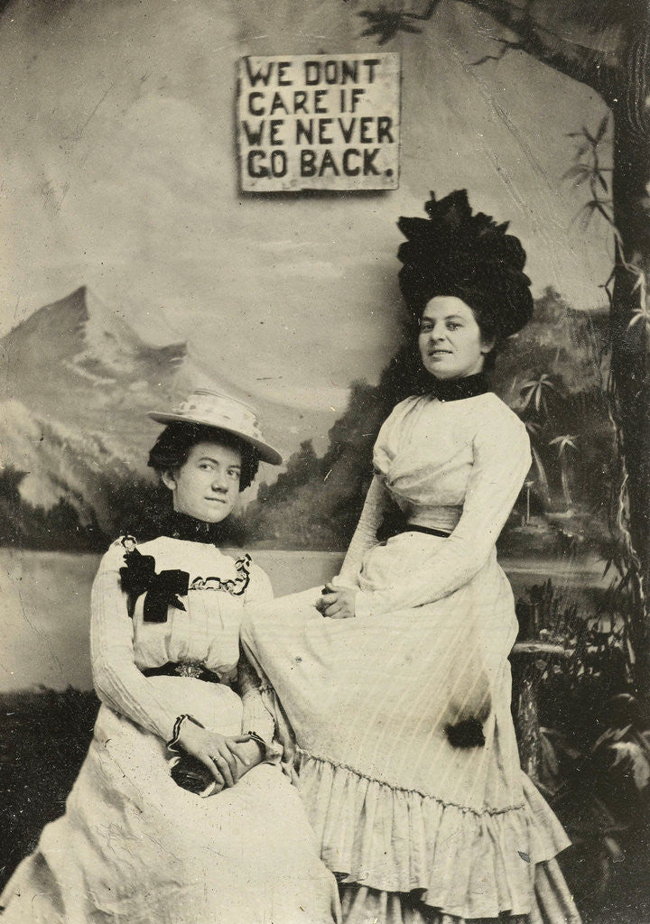 Detail of Portrait of two women standing and sitting in front of a painted backdrop (mountains) and the text WE DO NOT CARE IF WE NEVER GO BACK by Anonymous