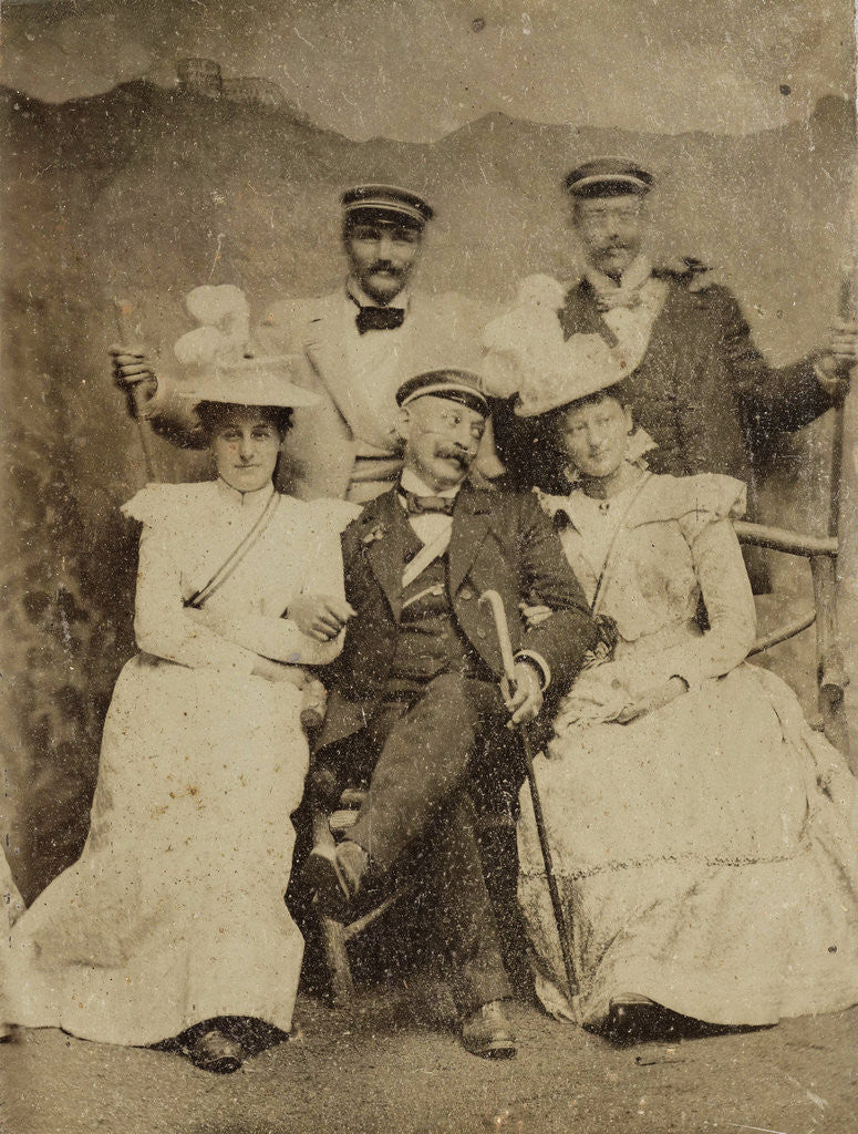 Detail of Group portrait of three men and two women in visible cheerful mood, standing and sitting in front of a painted backdrop showing a mountain castle by Anonymous