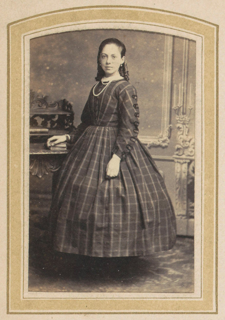 Detail of Portrait of a girl in a checkered dress at a table with books by A. Boeseken