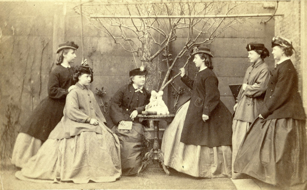 Detail of Group portrait of six young women in garden round table with sculpture, hats and coats by L. de Koningh