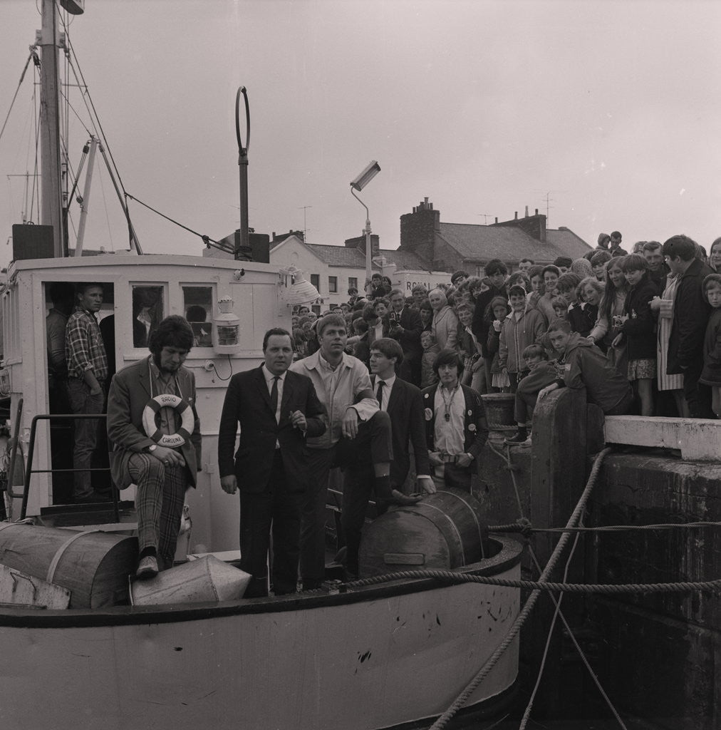 Detail of Radio Caroline disc jockeys Dave Lee Travis (on left with life ring) and Tony Prince (right with badges on jacket) on boat, Ramsey harbourside by Manx Press Pictures