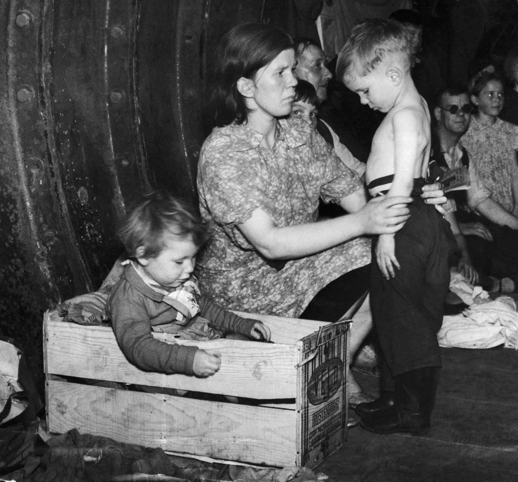 Detail of A mother tends to her young son in an underground bomb shelter during an air raid by Staff